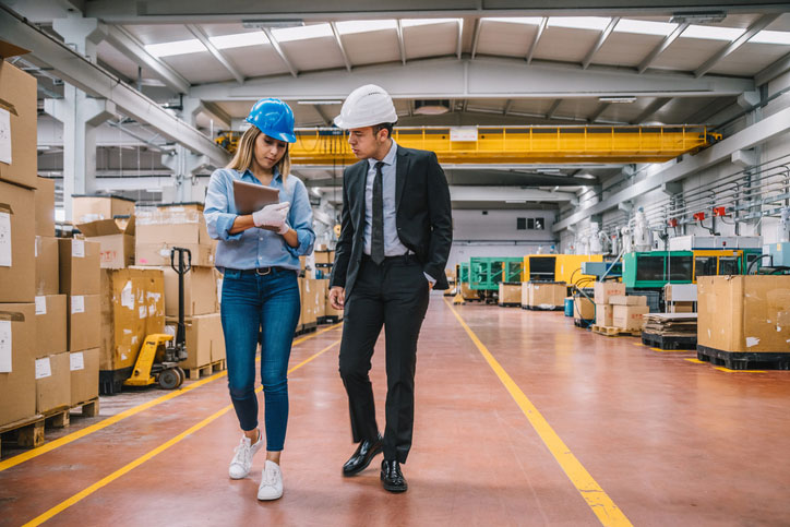 supply chain manager and coworker walking through warehouse on tablet