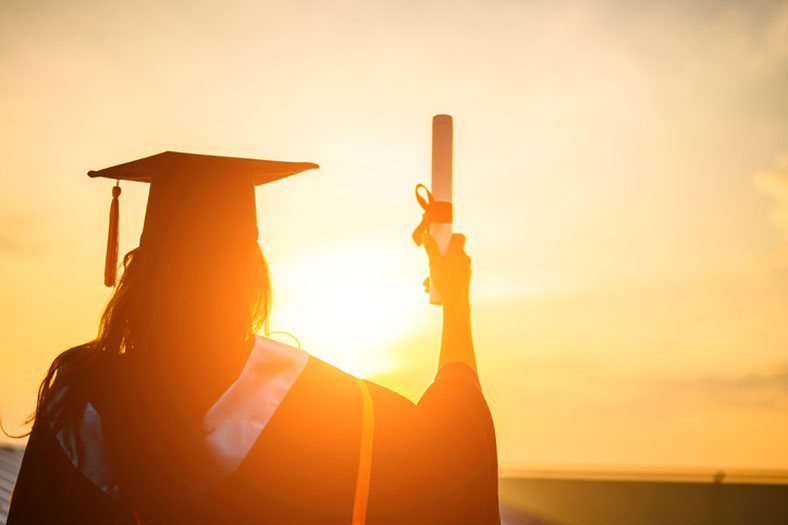 grad at sunset with diploma