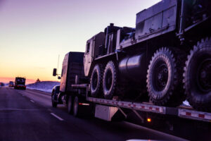 military truck on flatbead going down highway