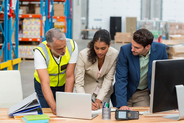warehouse managers and workers looking at laptop