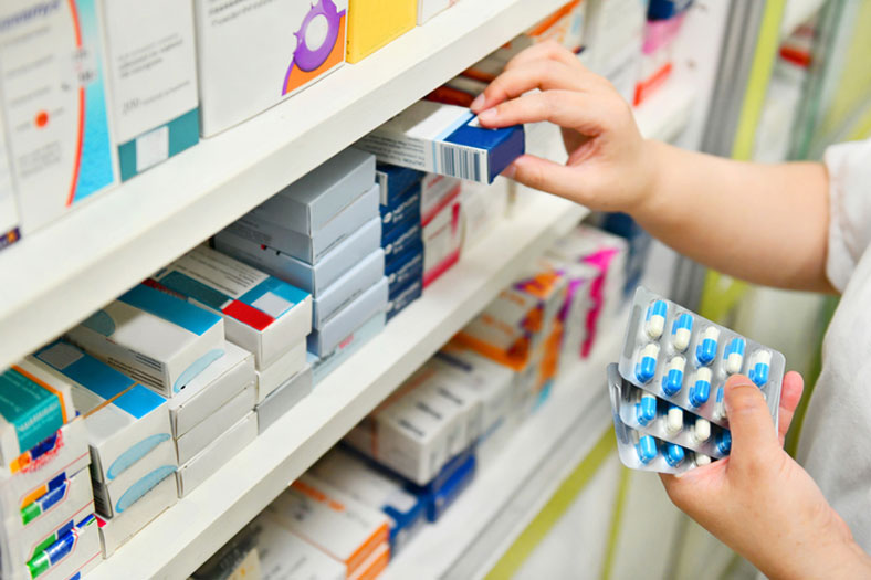 pharmacist pulling prescriptions from shelf