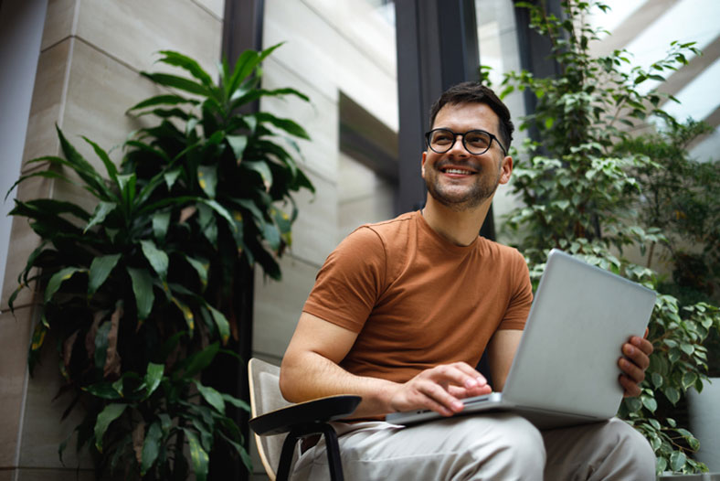 young man studying with laptop on bench